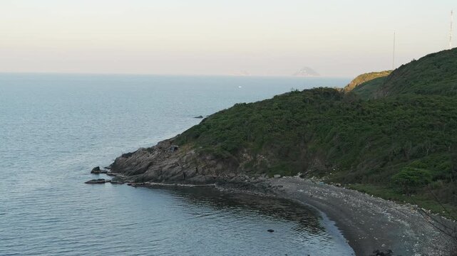 Rugged coastal wilderness with rocky headland and pebble beach at dusk for adventure trekking