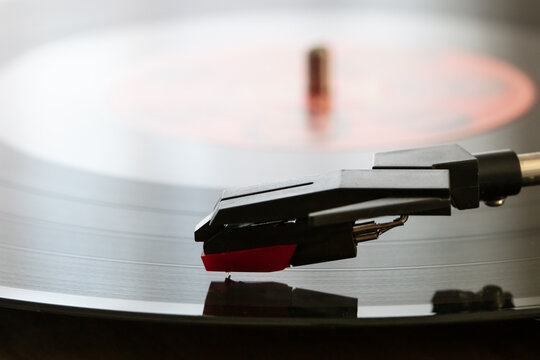 detail of a turntable with cartridge and 33 rpm vinyl record in the foreground