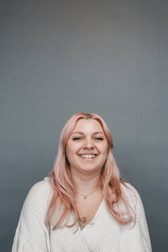 Portrait of smiling woman with dyed long hair against gray background