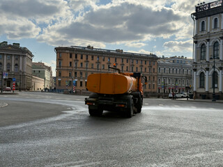 Obraz premium Rear View of Orange Tanker Truck Washing City Street Surface in Saint Petersburg Urban Landscape