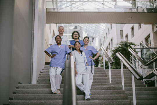 Portrait of smiling medical team of male and female staff standing on stairs in hospital building