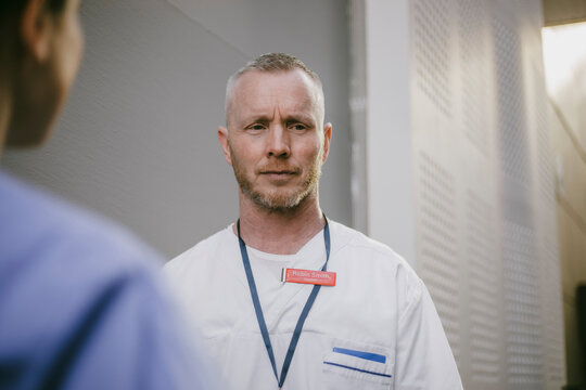 Confused male medical expert standing with female colleague in hospital lobby