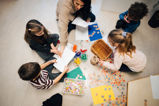 Directly above view of female teacher doing fun and interactive session with elementary students sitting in classroom