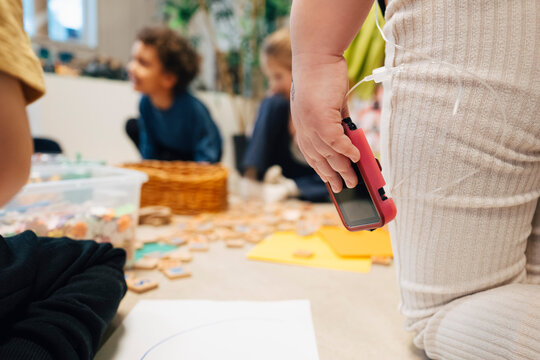 Midsection of girl holding insulin pump while kneeling on classroom floor