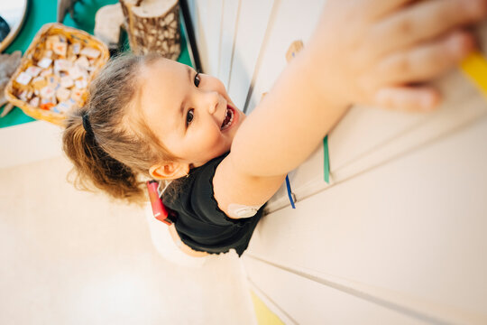 High angle view of happy girl with insulin pump doing height test near wall in classroom