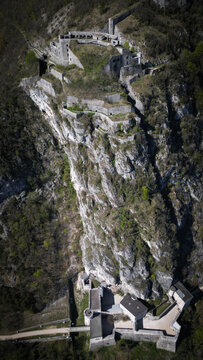 Aerial view of the stark white ruins of Fort l'Ecluse clinging to the rugged, green-clad cliffs, a testament to history's enduring presence, Leaz, Auvergne-Rhone-Alpes, France.