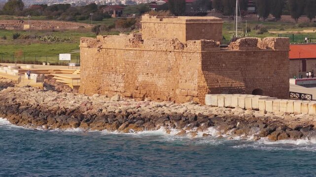 Aerial drone view of a historic stone castle located on rocky coastline with waves in Paphos, Cyprus