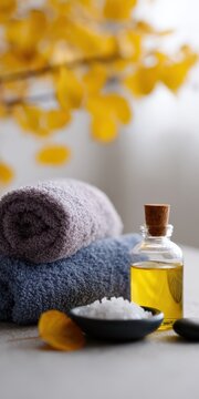 Fall spa vignette blue and gray towels glass bottle of golden oil bowl of sea salt and yellow ginkgo leaves for natural wellness and relaxation