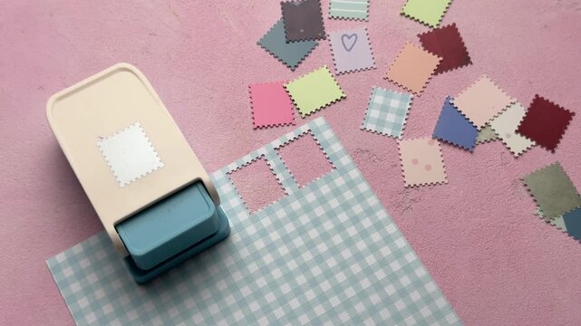 Craft punch creating postage stamp shapes from paper
