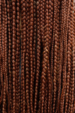 Rear view of a person with long reddish-brown box braids or dreadlocks wearing a blue denim jacket outdoors, close up for hairstyle, ethnic beauty, fashion, and hair care concept. vertical