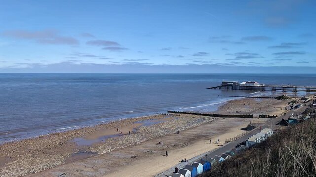 Scenic view of Cromer Pier with sandy beach in the foreground along the North Sea coast in Norfolk, showcasing a classic British seaside landscape and coastal architecture on a clear day