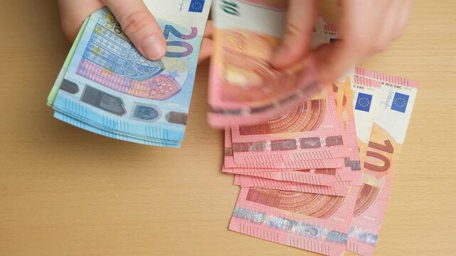 Counting a stack of euro banknotes on the table.