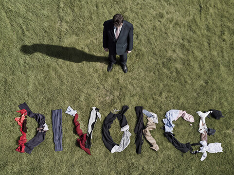 Business man stood over his shredded clothes in the shape of the word 'Divorce' cheating, infidelity concept