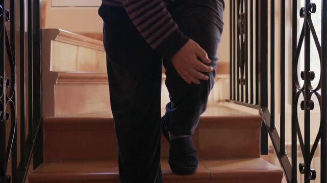 Man feeling leg pain while walking down the stairs