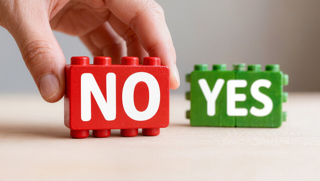 Hand Placing Red 'NO' Block Next to Green 'YES' Block on Wooden Table