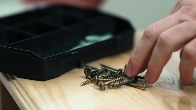 Man's hand picking up fastener from toolbox compartment, furniture assembly process, professional 10-bit 4K UHD.