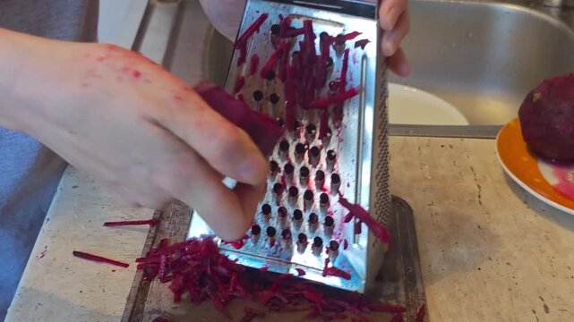 Making shredded beets in the kitchen with a grater for salads and dishes