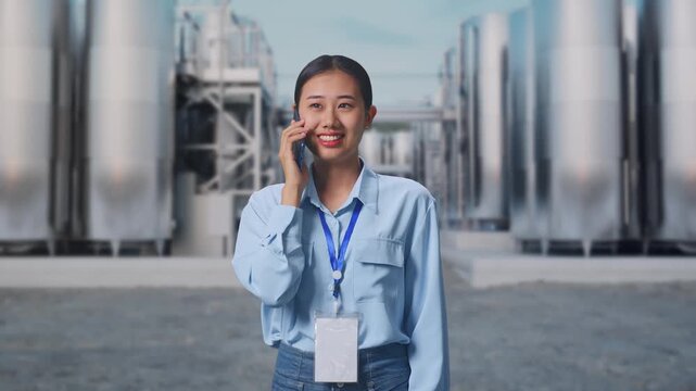 Asian Female at Chemical Plant with Row of Stainless Steel Storage Silos, She Pick The Phone Up And Started To Speaking With It