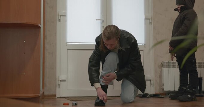 Man and child put on footwear winter shoes. 4K 10-bit