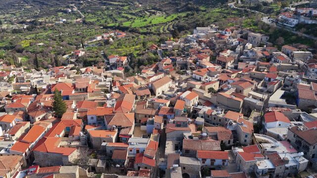 Aerial drone view of a traditional Cypriot village featuring a historic church with bell tower and red tiled roofs. Pano Lefkara, Cyprus