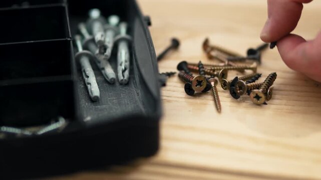 Man's hand picking up fastener from toolbox compartment, furniture assembly process, professional 10-bit 4K UHD.