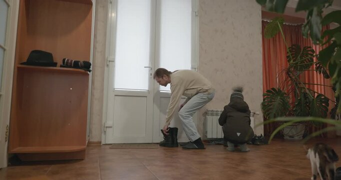 Man and child put on footwear winter shoes. 4K 10-bit