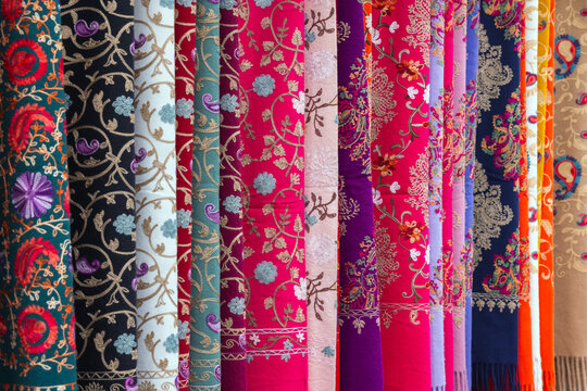 Vividly patterned traditional Azerbaijan fabrics displayed in a retail environment, showcasing their intricate detail, bright colors, and luxurious material, ideal for illustrating textiles 