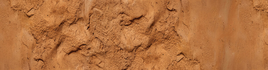 Fototapeta premium Close-up of Natural, Rough-Textured Terracotta Clay and Mud Wall with Organic Fissures, cracks, and Ooze Folds.