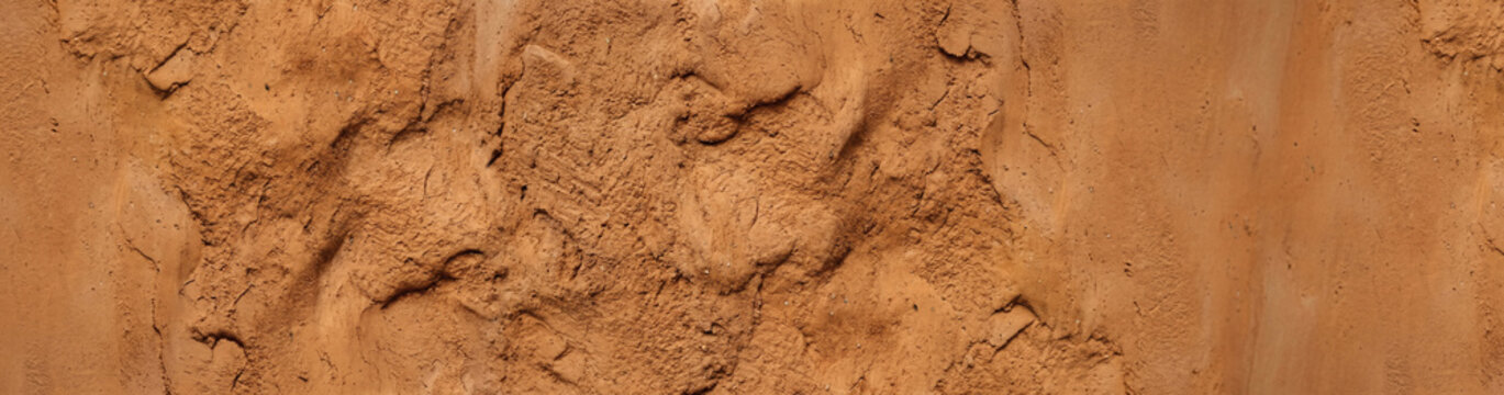 Close-up of Natural, Rough-Textured Terracotta Clay and Mud Wall with Organic Fissures, cracks, and Ooze Folds.