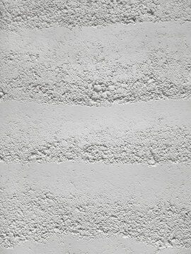 Background of texture rammed white earth wall with uneven, rough, horizontal grain pattern. Environmentally friendly building material with a minimalist aesthetic for modern architecture or interiors.