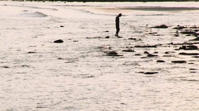 silhouette of man walking on coastline at dawn Thailand