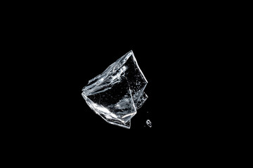 Fototapeta premium Frozen Brilliance: A translucent ice shard shimmers, its crystalline structure catching the light, appearing suspended in a dark, infinite void.