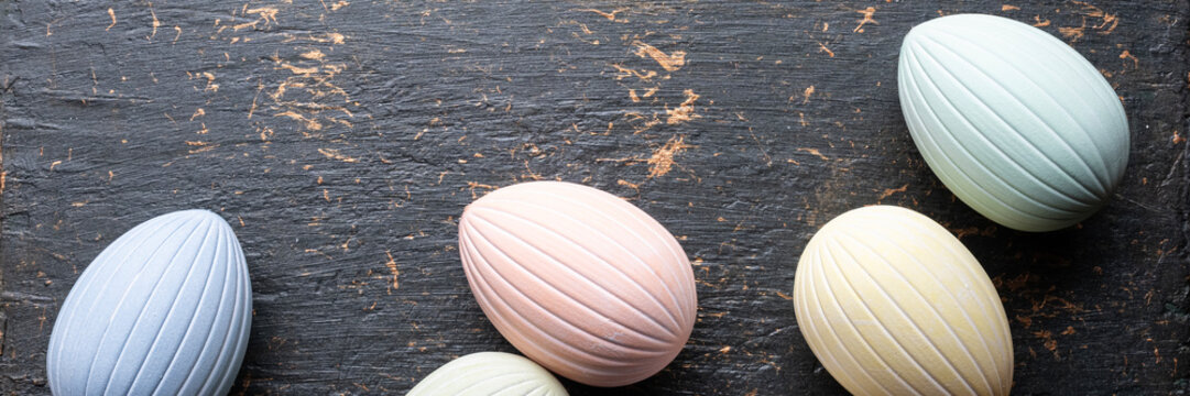 Pastel easter eggs banner on dark rustic background with copy space