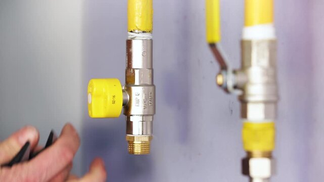 Technician Installing New Gas Ball Valve on Yellow Pipe. Professional hands fitting a brass shut-off valve during gas line upgrade.