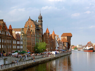 Fototapeta premium Panoramic view of the Motlawa river embankment in Gdansk with historic granaries and the Crane. Popular tourist destination in Poland with beautiful old architecture.