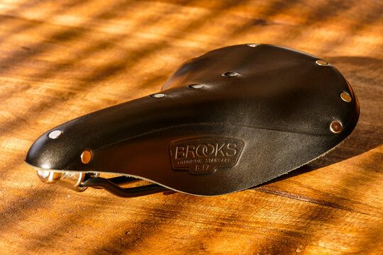 Brooks B17 standard black leather bicycle saddle on wooden table, side view