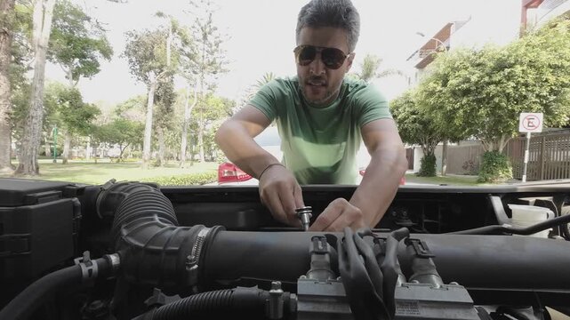 Man using a socket wrench to repair a car engine outdoors