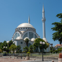 Obraz premium The modern Ebu Beker Mosque stands prominently with its striking silver dome and tall twin minarets against a brilliant blue sky in Shkoder, Albania.