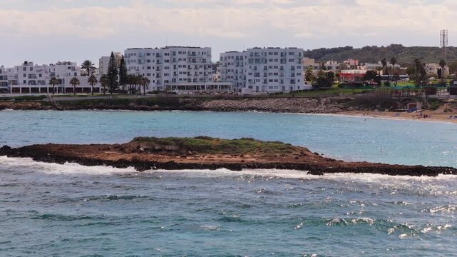 Aerial drone view of a small rocky islet surrounded by waves off the coast of Protaras, Fig Tree beach, Cyprus
