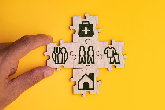 wooden cube with icons of food, Clothing, housing, medical bag, four basic human needs concepts. The Four Basic Material Needs of the Human Being.
