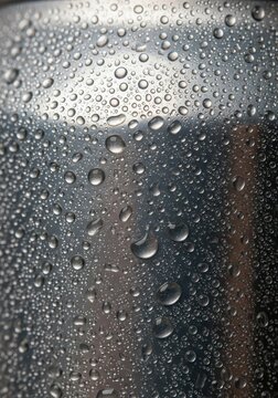 Cold condensation droplets cover the textured surface of a metallic container.