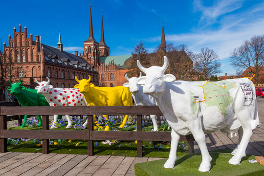 Colourful cow sculptures on a background of Roskilde cathedral, Denmark