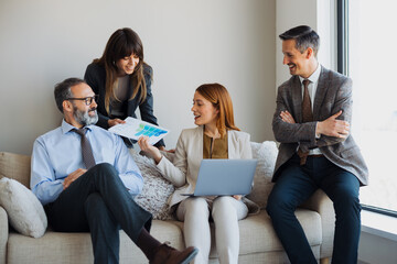 Group of diverse business colleagues sitting on a comfortable sofa in a modern office lounge,...