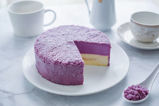 A vibrant and delicious taro cheesecake, showcasing beautiful purple and white layers, with a slice removed to reveal its creamy texture.
