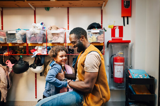 Side view of father kneeling and holding son during first day of school