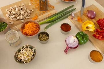 Kitchen countertop displaying assorted vegetables, spice bowls, cutting boards and chef knife © wavebreak3