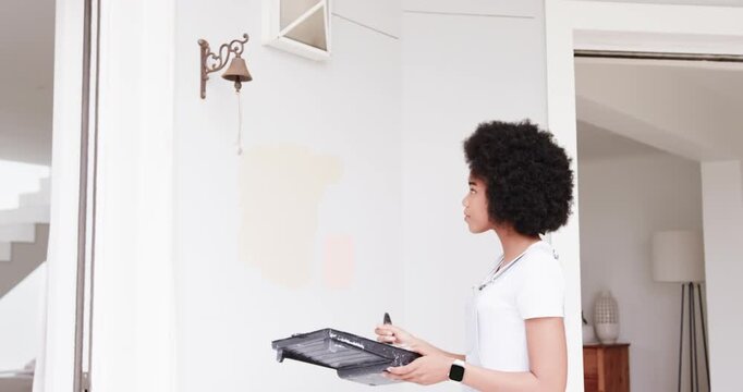 Seeing bell, African woman in apron holding tray, brush, testing samples and picking color at wall