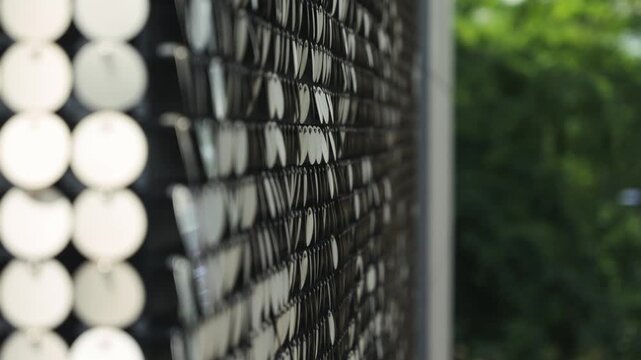 Reflective circular pattern. Metallic, reflective, circular discs, sequins or reflective panels, arranged in a grid pattern on the facade of a modern building.
