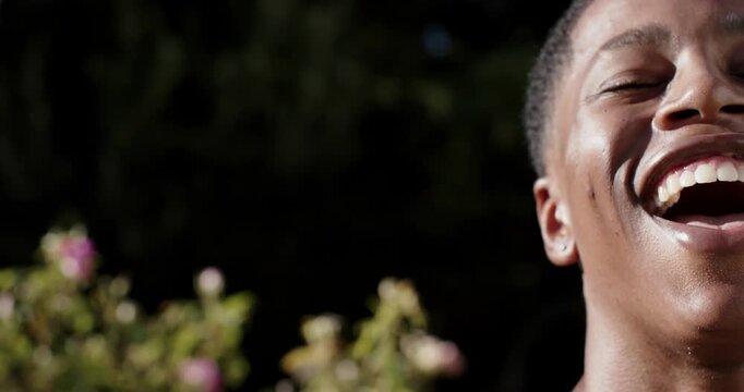 African American man smiling laughing reacting to offscreen voice in garden, ear stud, copy space