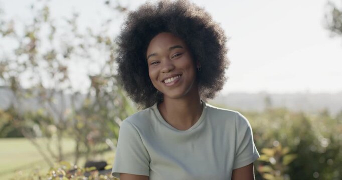 Camera cueing African-American woman smiling laughing folding arms in green tee and hoops in park